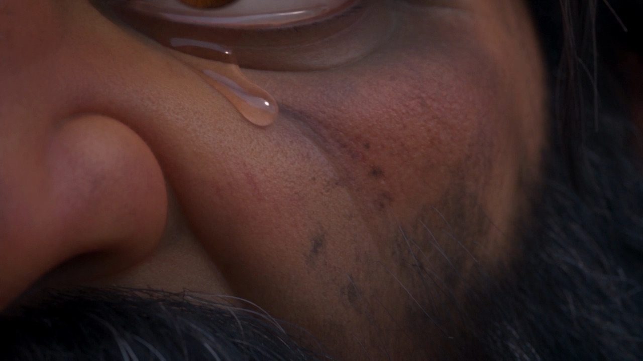 A tear runs down the weathered cheek