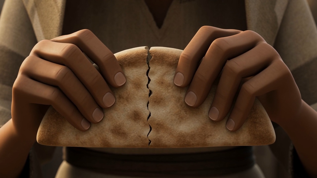Two hands breaking one flatbread carefully in half